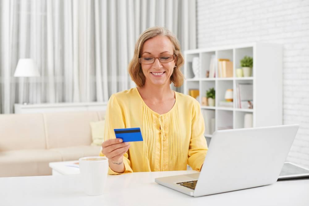 femme devant ordi avec carte de banque en main